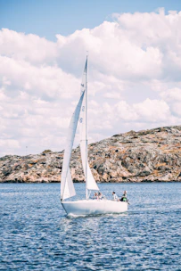 Sailing club members navigating a sailboat on a sunny Croatian coastline.