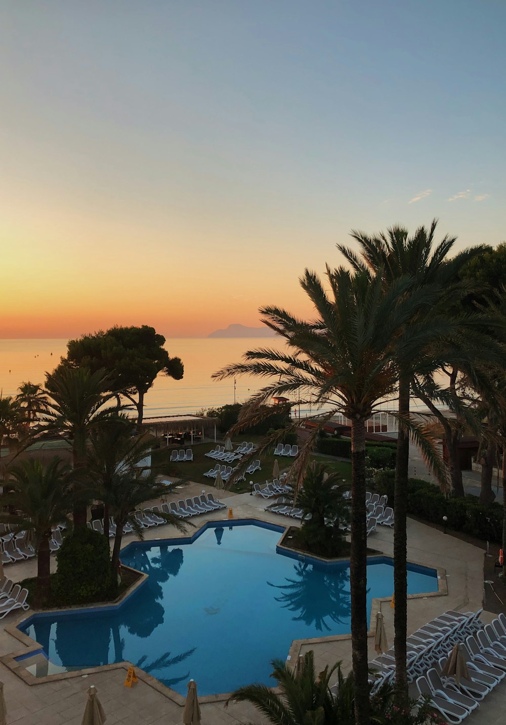 blue outdoor swimming pool at sunset