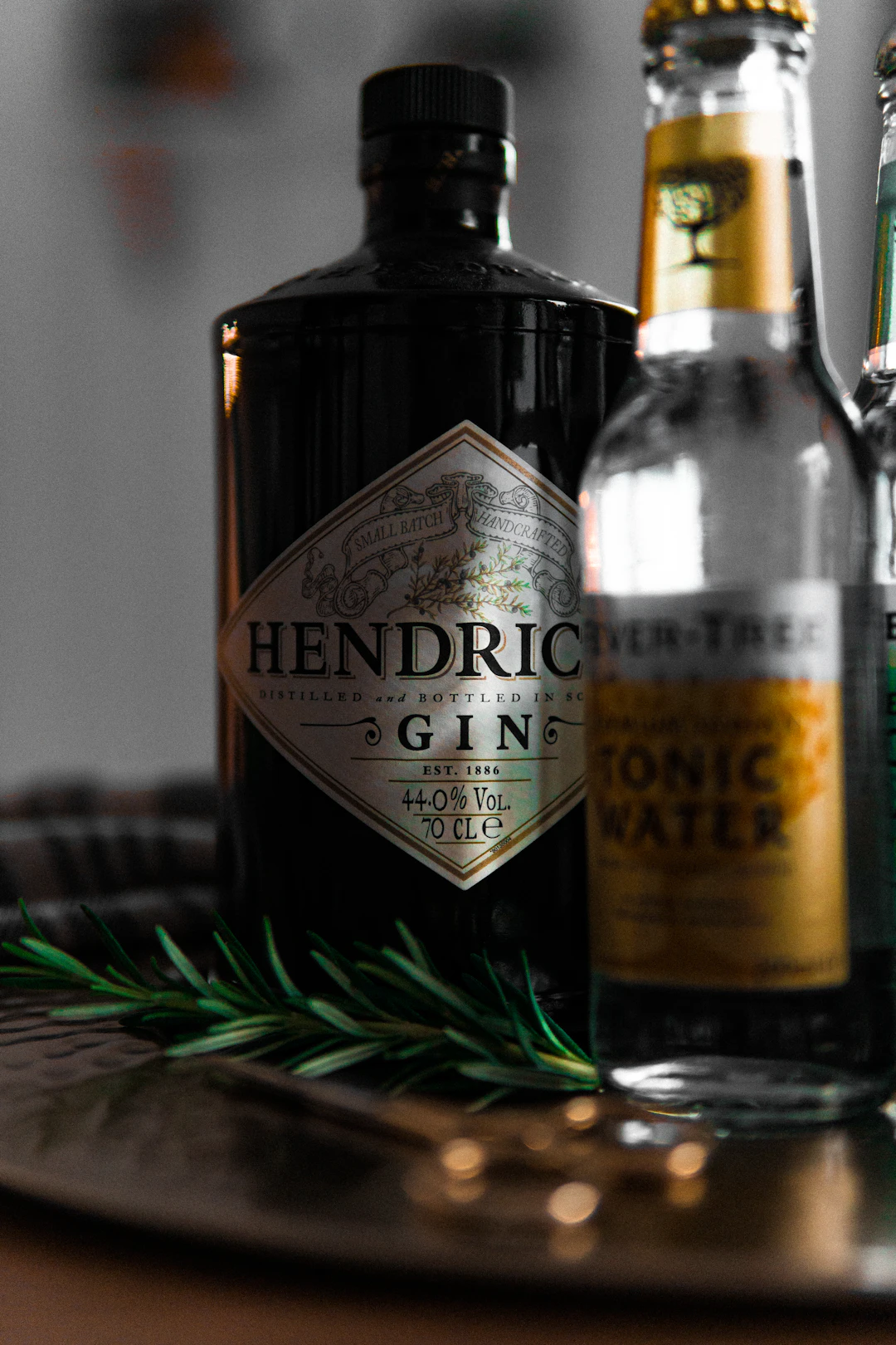 Gin-Flasche mit Tonic und Rosmarin im Barlicht