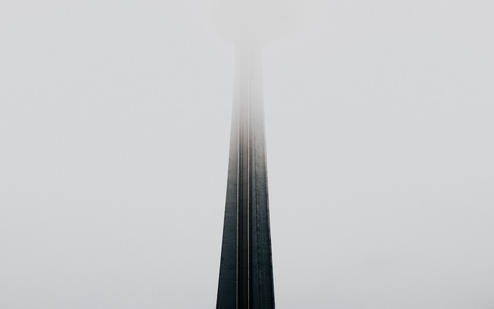 a very tall tower in the middle of a foggy sky