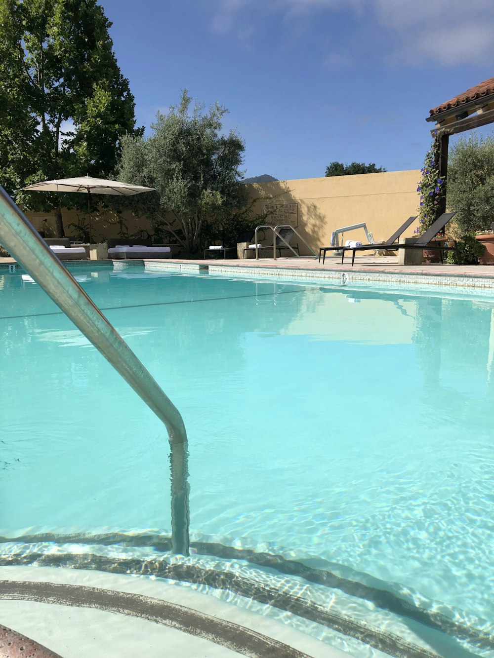 swimming pool with lounge chairs and parasol during day