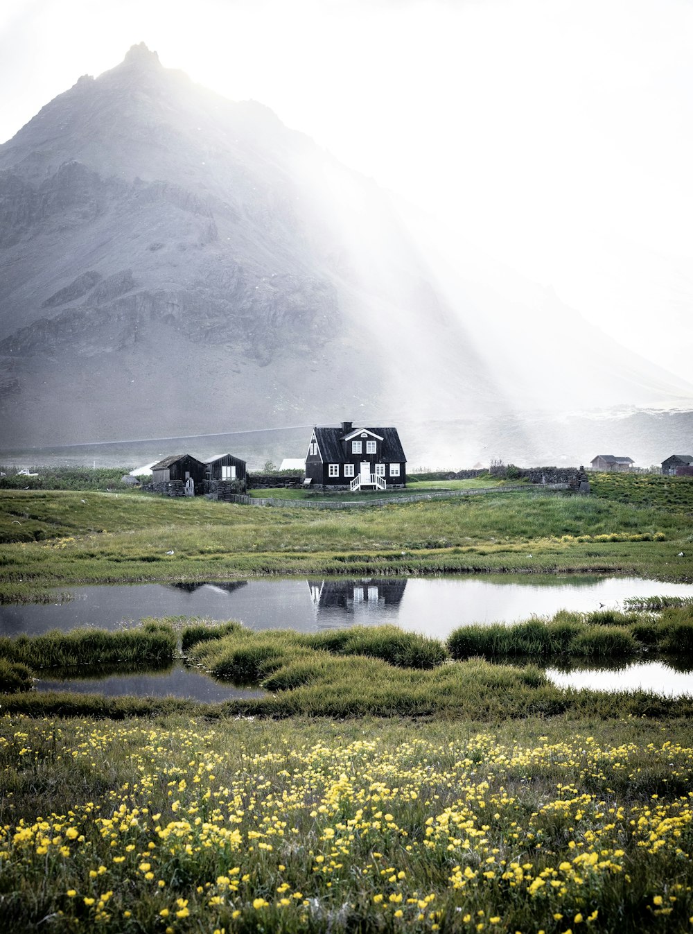 black house near body of water with mountain at distance