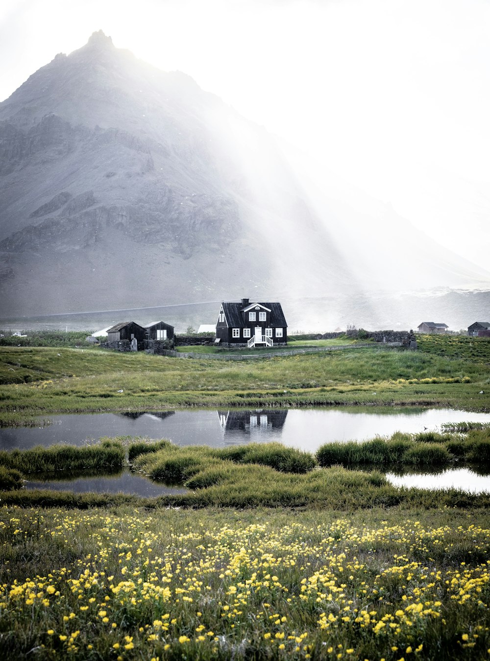 casa nera vicino allo specchio d'acqua con la montagna a distanza