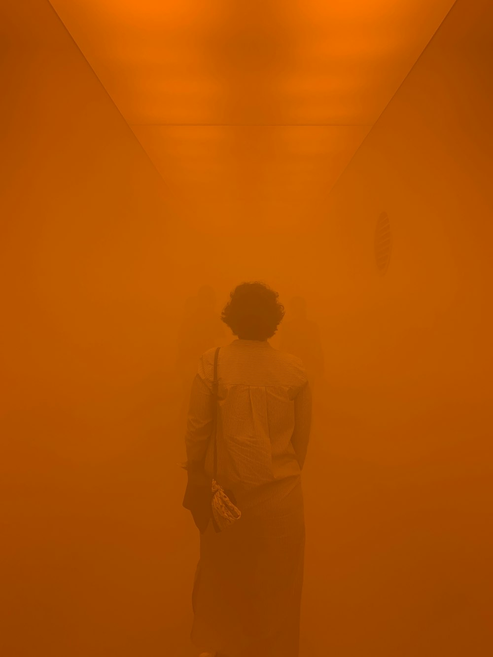 Fotografía borrosa de una persona dentro de una habitación naranja