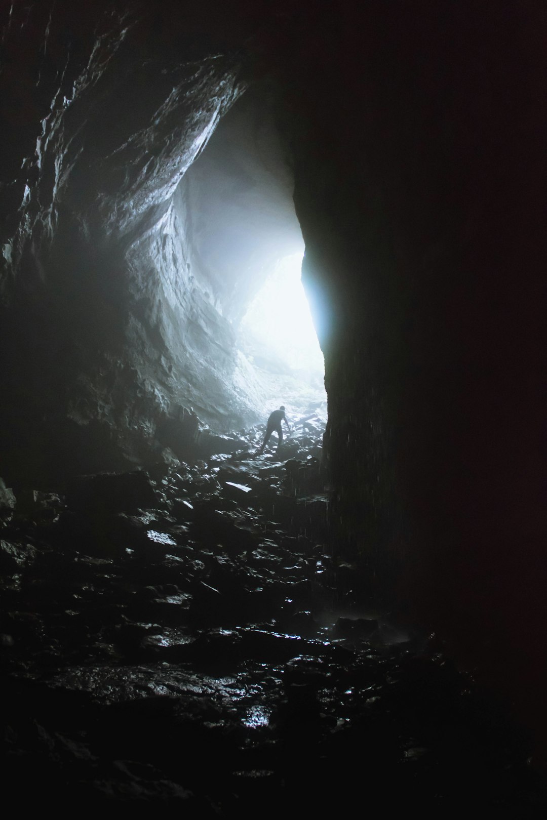 a person standing in a dark cave with light coming through