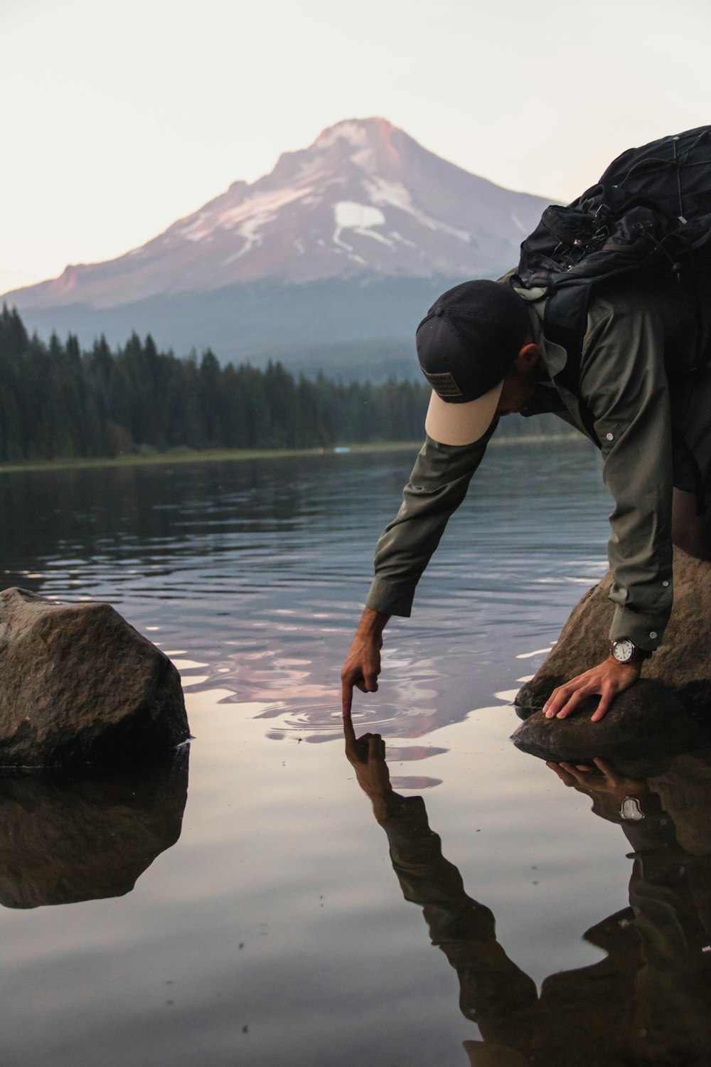 man putting finger on water viewing mountain