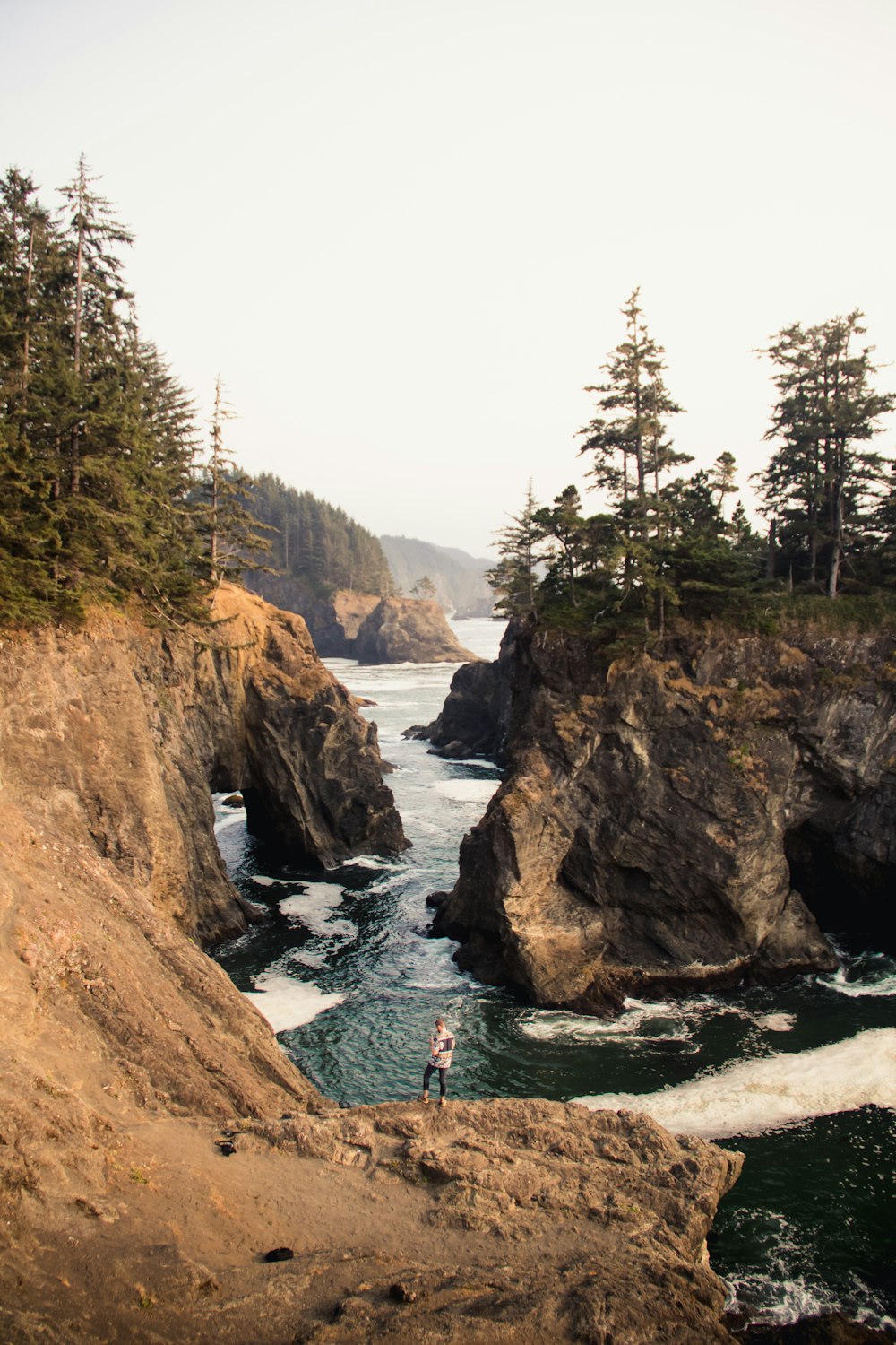 man standing at the edge of rock near rive r