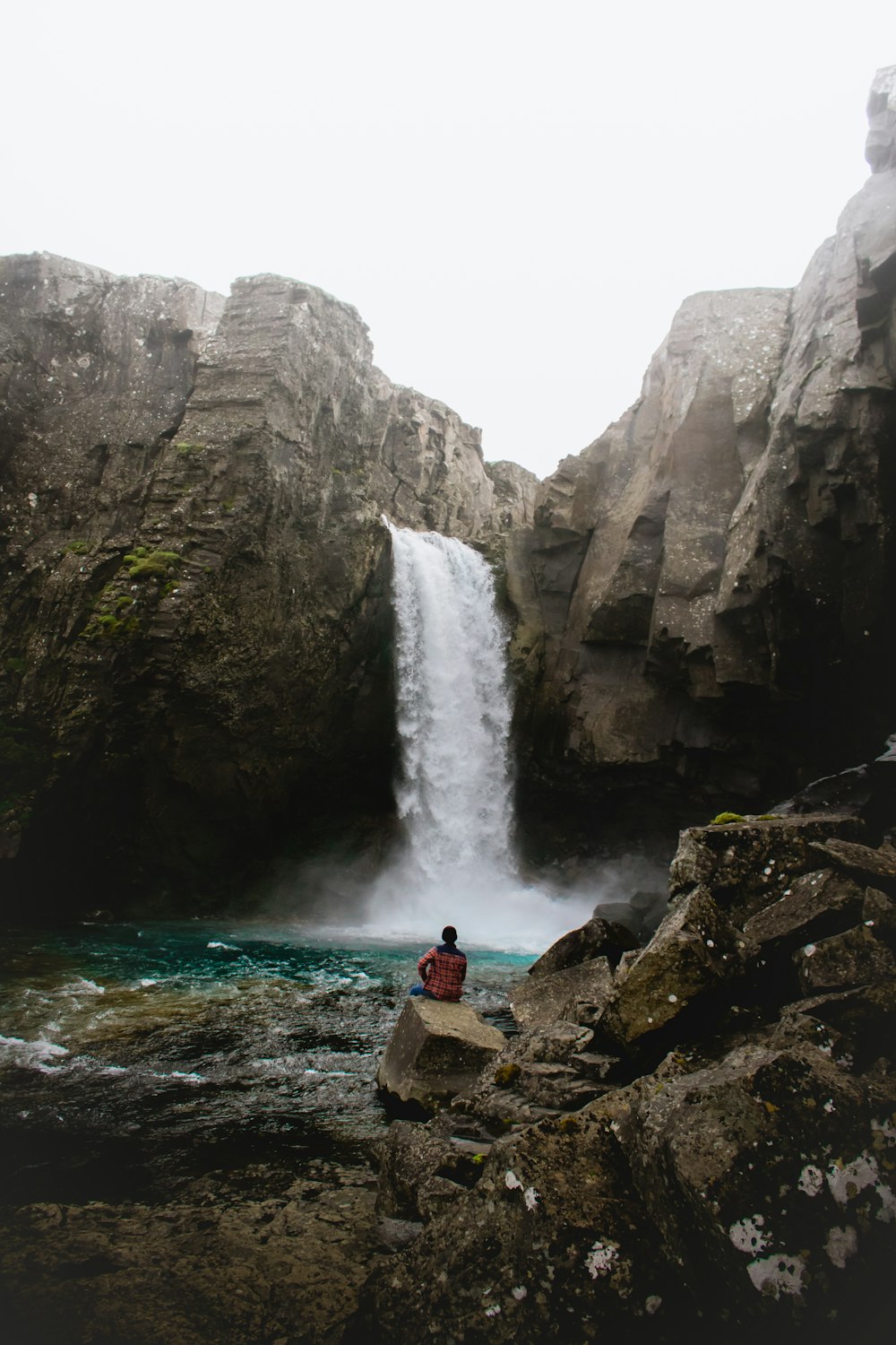 man siting near waterfall