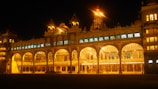The majestic Mysore Palace illuminated at dusk, showcasing its intricate architecture.