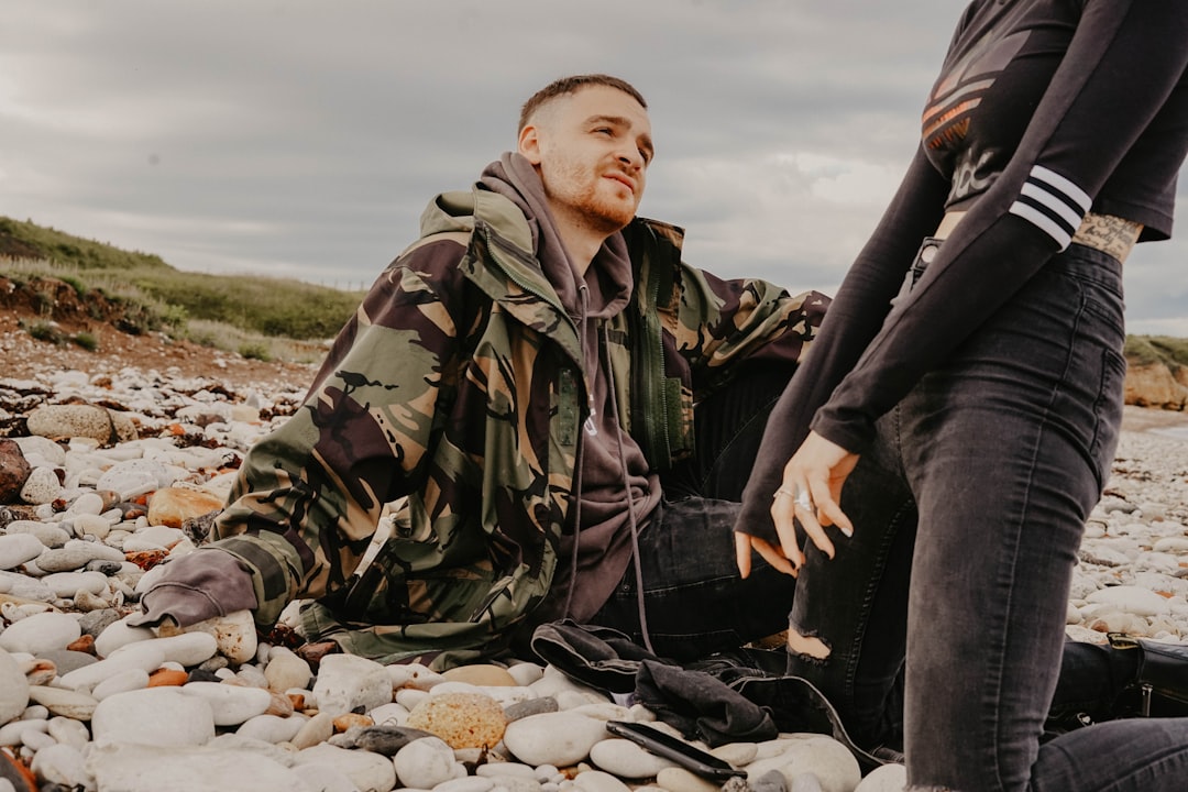 woman kneeling on stones beside man in camouflage jacket