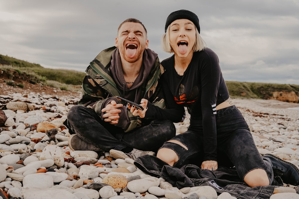 man and woman on stone field showing tongues during daytime