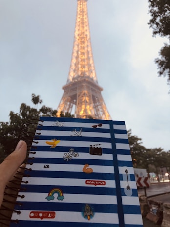 A smiling child holding a whimsical notebook surrounded by crayons and stickers.