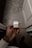 A hand is holding a white wireless earphones case against a modern tiled floor backdrop. The earphones are neatly packed inside the case.