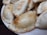 Several golden-brown baked pastries are neatly arranged on a white plate. The pastries have a semi-circular shape with crimped edges, showing a glossy, evenly baked surface.