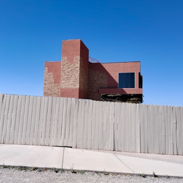 Small commercial building with new blue and white fencing along the perimeter.