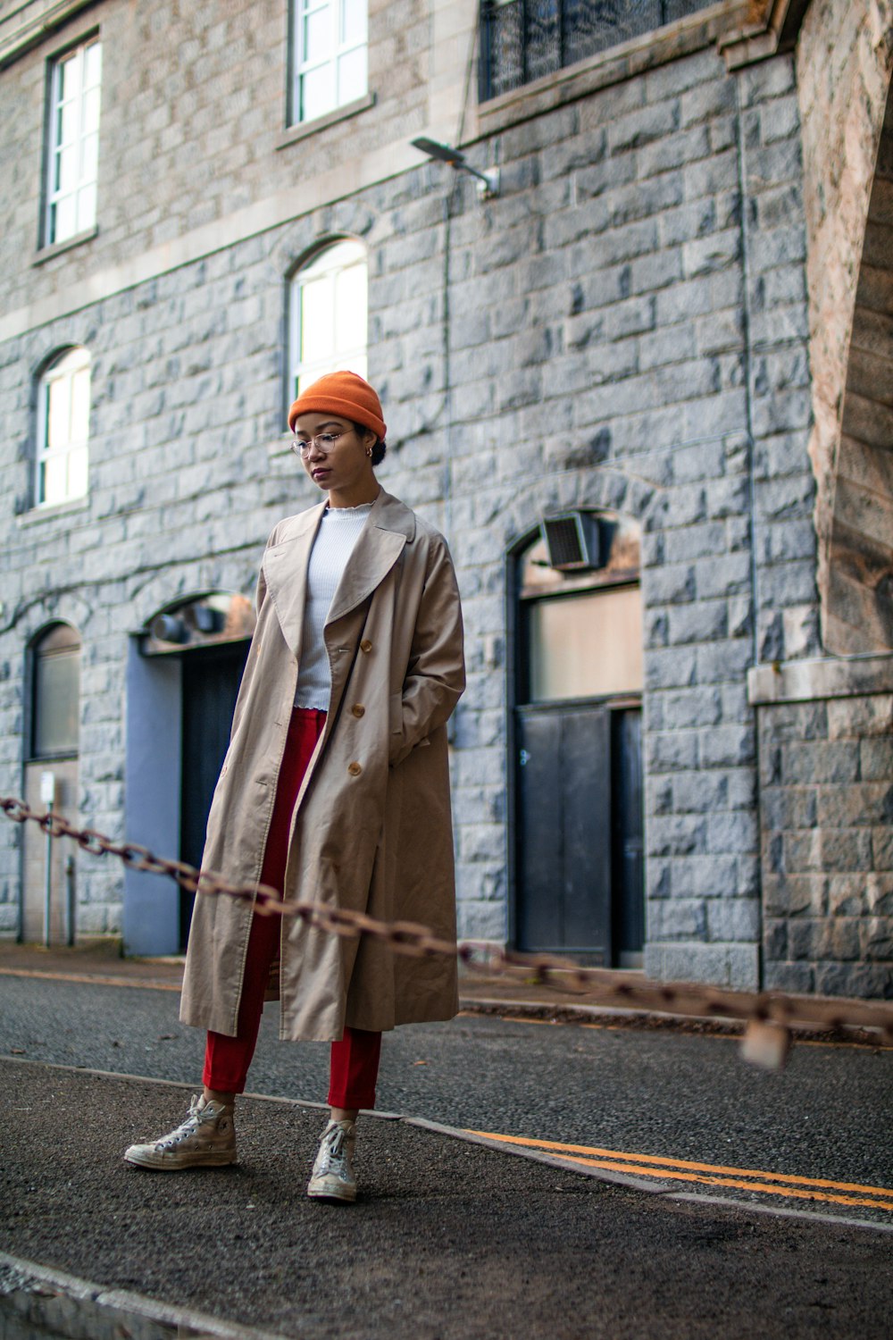 woman wearing brown coat standing besides brown steel chain