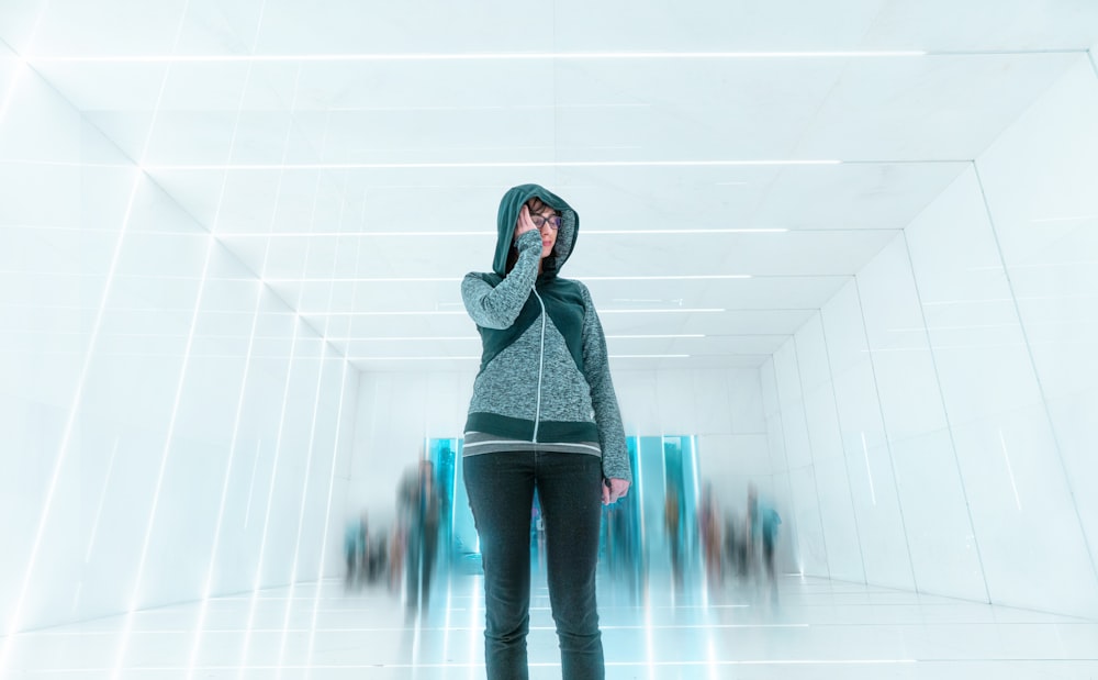 person wearing gray and black full-zip hoodie standing on white room