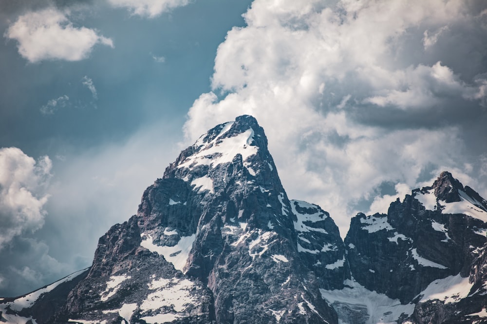 photo of white and black mountain across white clouds