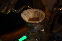 Close-up of freshly brewed coffee dripping into a glass from a pour-over setup.