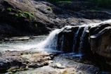 The 12-foot waterfall cascading into a serene pool surrounded by mossy rocks.