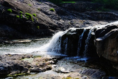 The 12-foot waterfall cascading into a serene pool surrounded by mossy rocks.