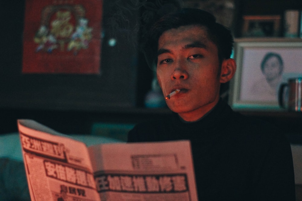man wearing black turtleneck holding newspaper