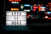 Less Is More signboard across blurry city lights