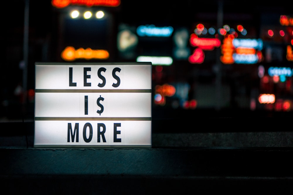 Less Is More signboard across blurry city lights