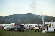 Family enjoying a campfire beside their Voyagecraft caravan in a lush forest setting at dusk.