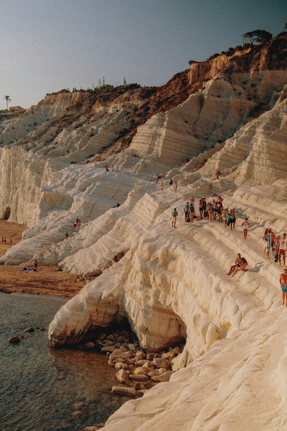 people in a rock formation near body of water during daytime