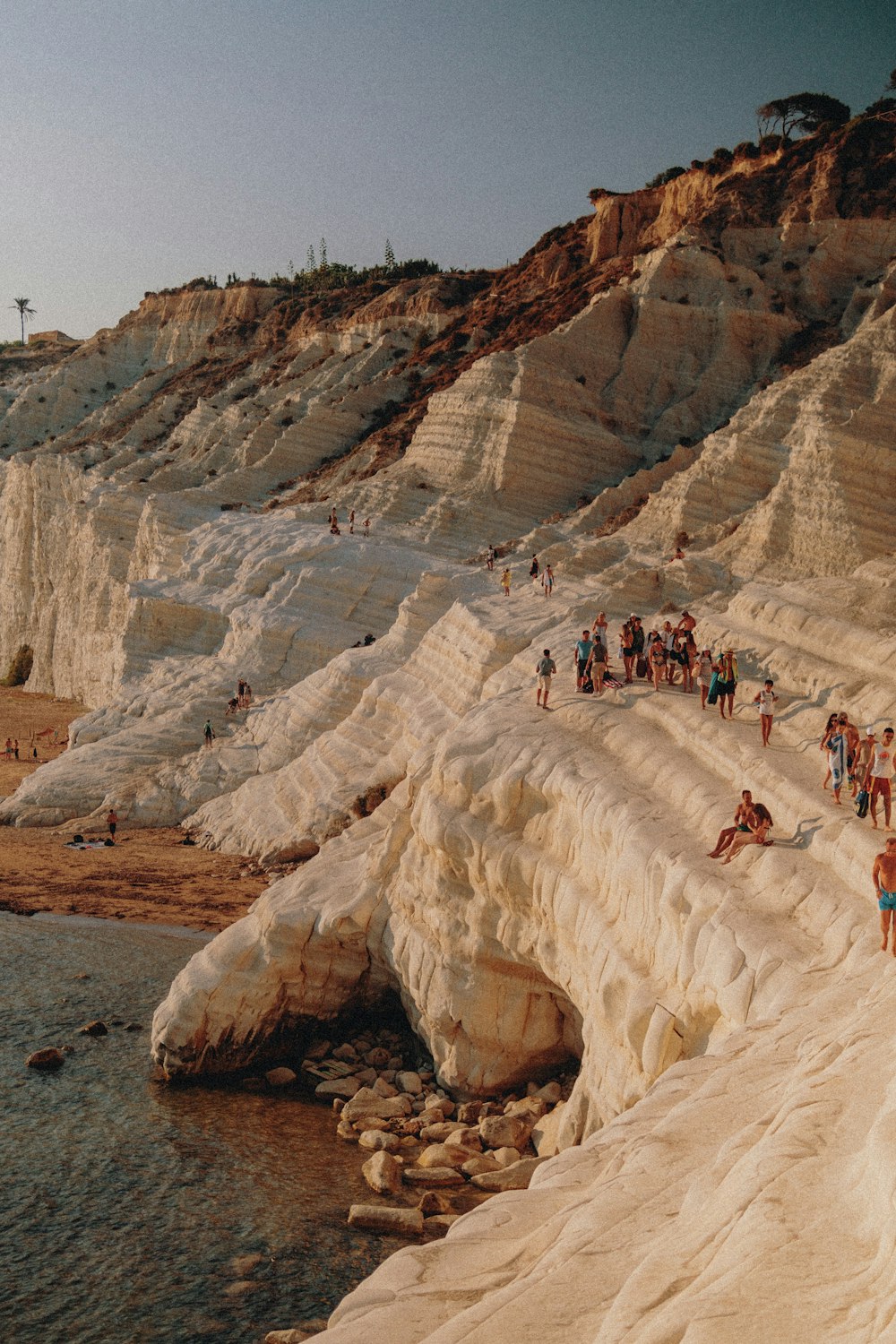 personas en una formación rocosa cerca de un cuerpo de agua durante el día
