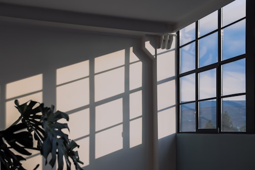 Sunlight casting the shadow of a window in a wall evoking a quiet moment of reflection