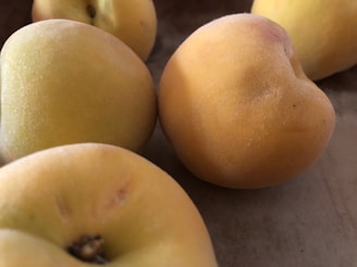 A close-up of ripe, golden peaches with soft fuzz on their skin, resting on a rustic table