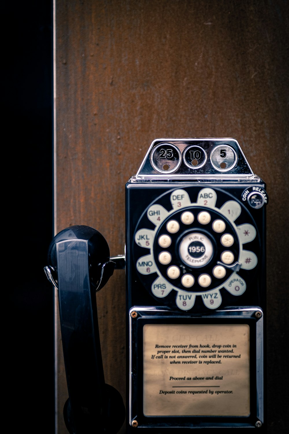 telefone de parede preto e branco na parede marrom