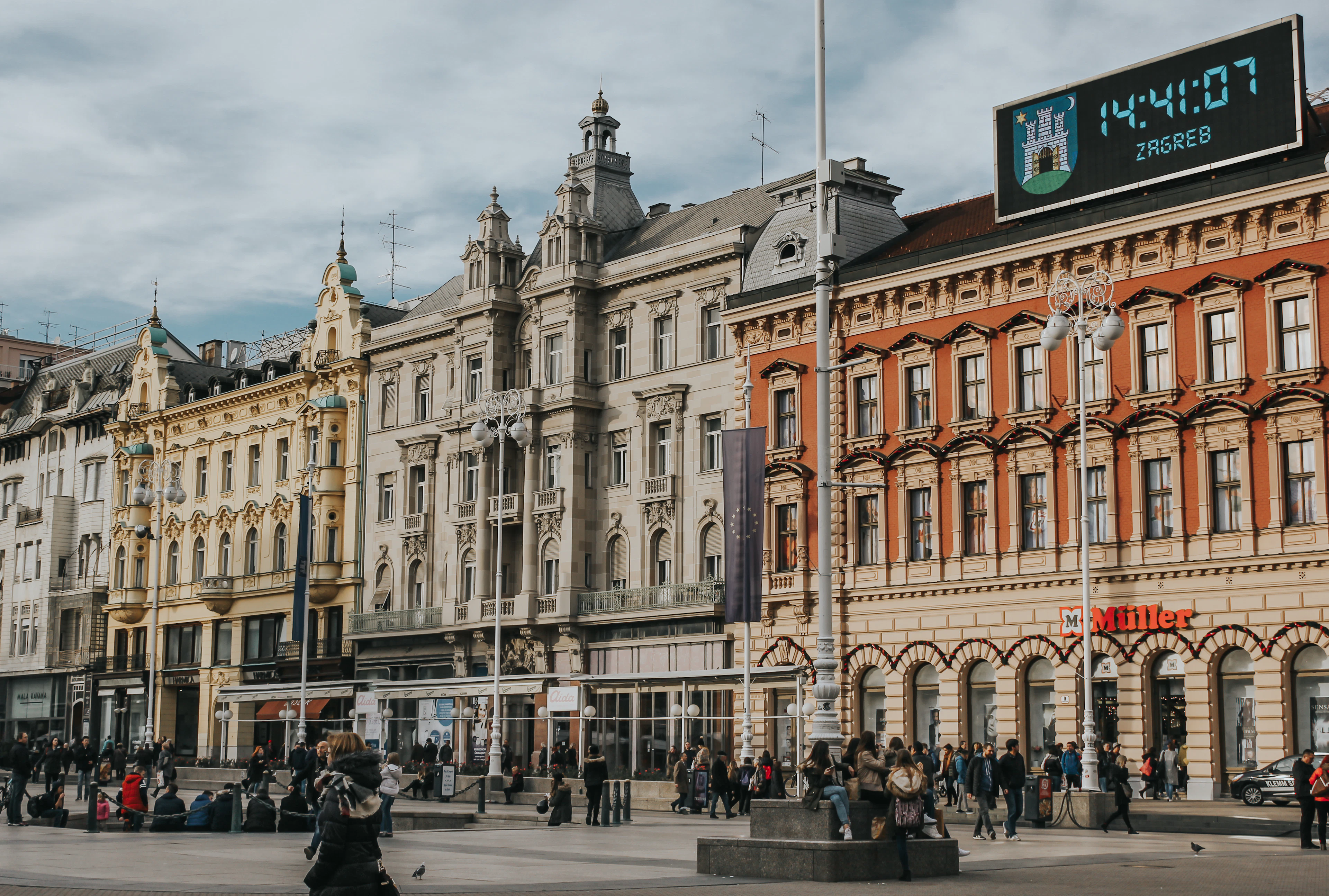 Ban Jelacic Square in Zagreb, pastel nineteenth-century facades and a digital display reading ZAGREB above the crowds