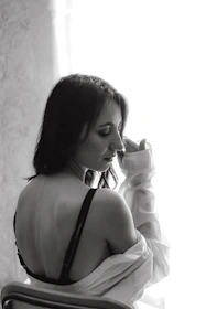 A candid moment of a woman smiling softly while wearing a seamless, comfortable bra in natural light.