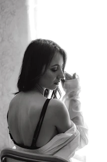 A candid moment of a woman smiling softly while wearing a seamless, comfortable bra in natural light.