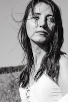 A black and white portrait of the bride smiling with her veil gently blowing in the breeze.