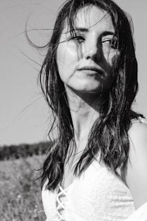 A black and white portrait of the bride smiling with her veil gently blowing in the breeze.