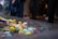 A variety of colorful plastic toys float in a clear rectangular water basin. The toys include ball-shaped objects and animals in bright colors such as yellow, blue, pink, and green. There is a partial view of a person standing nearby, wearing a blue striped garment.