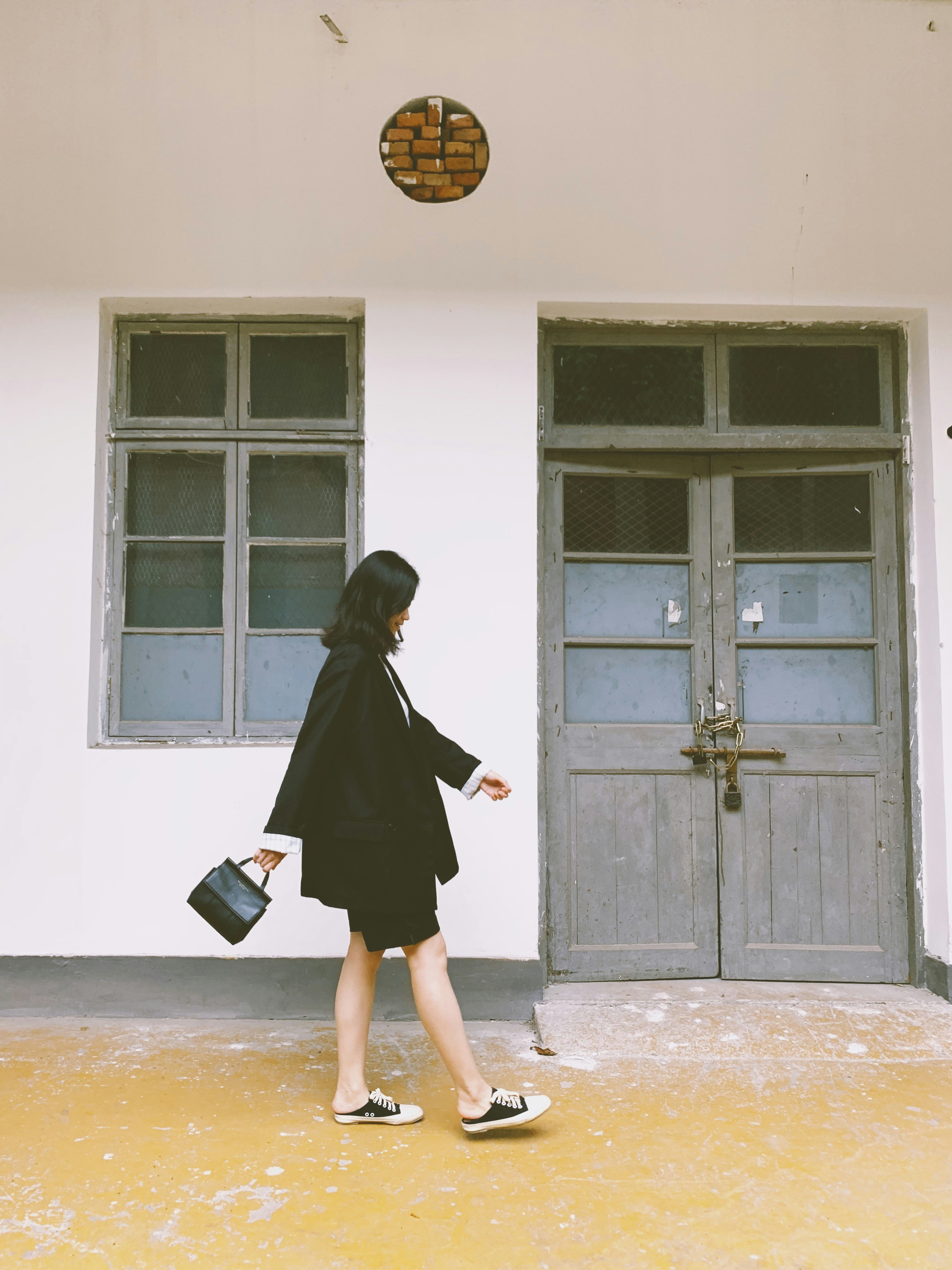 woman in black blazer walking and carrying black handbag