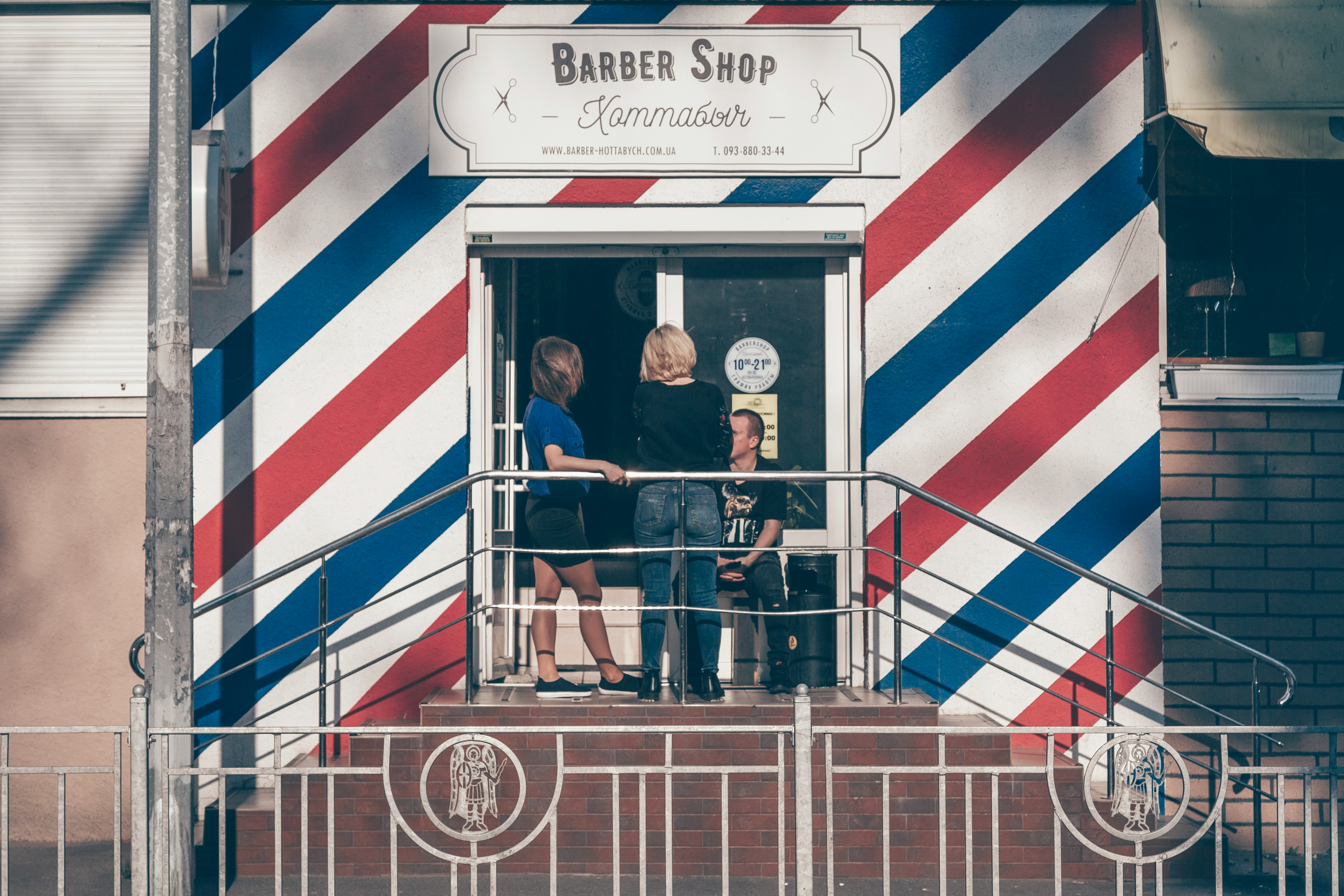 two women and man outside barber shop building