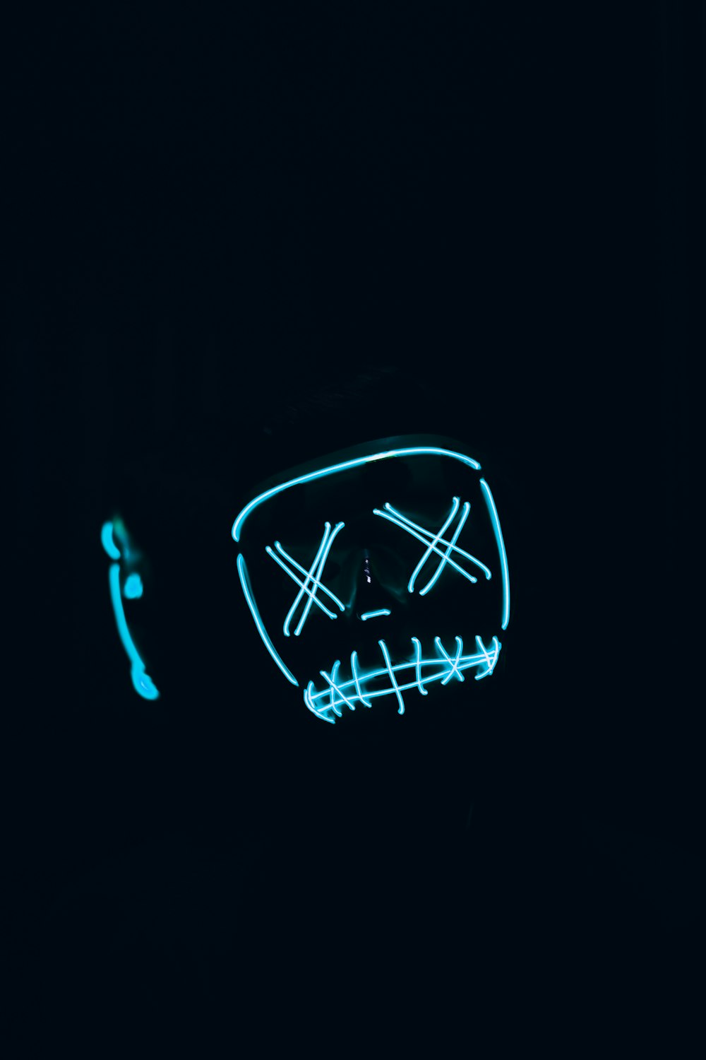 a neon mask is lit up in the dark