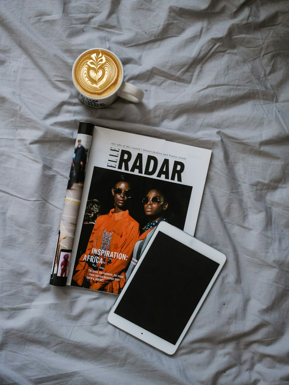 cappuccino near open magazine page and iPad Mini