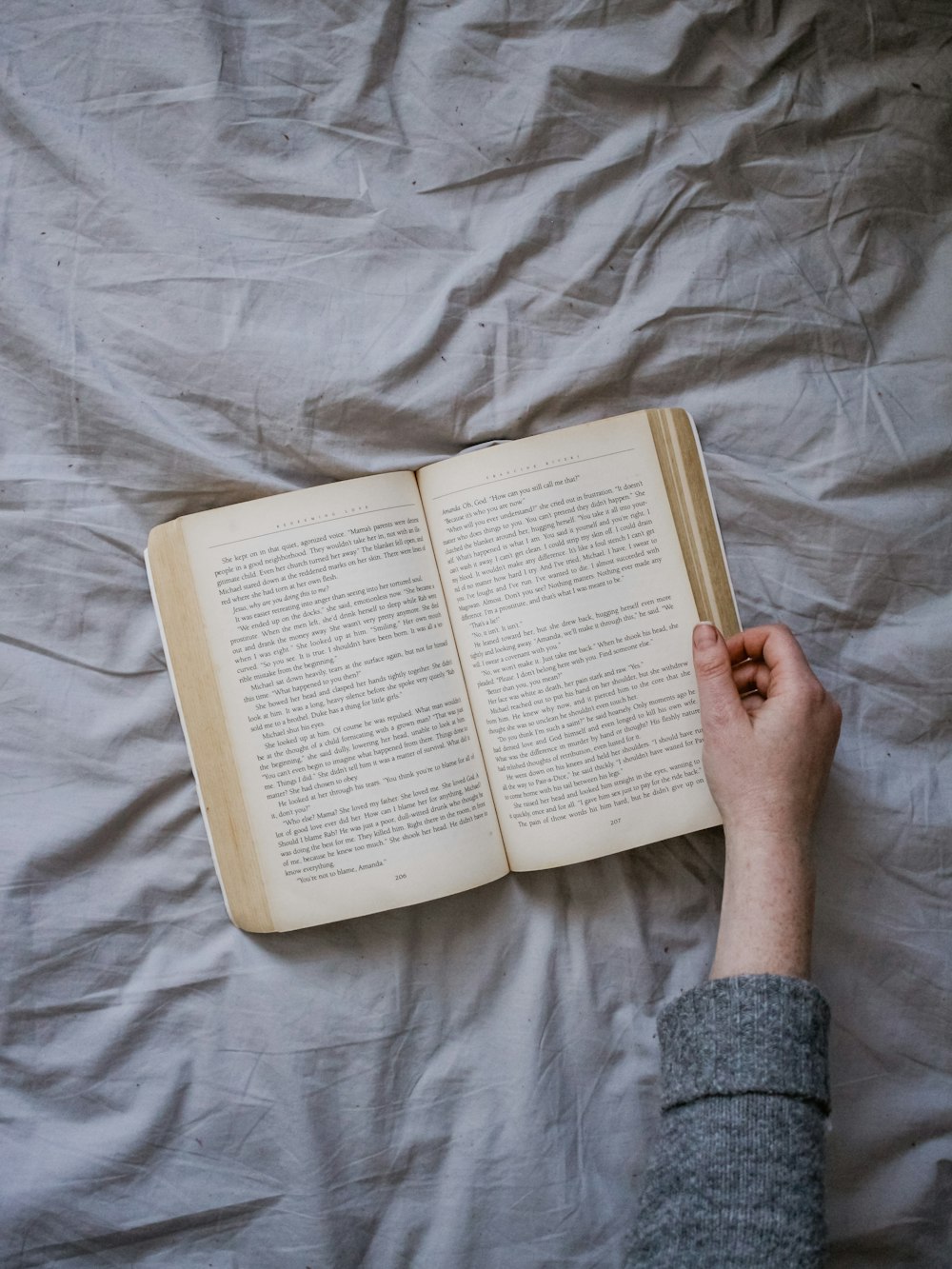 Person, die ein aufgeschlagenes Buch in der Hand hält