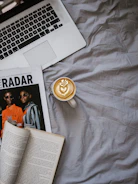 Modern laptop open on a desk with tech magazines and coffee cup nearby