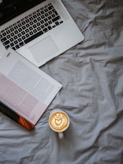 A warm cup of coffee beside a laptop displaying a blog post.
