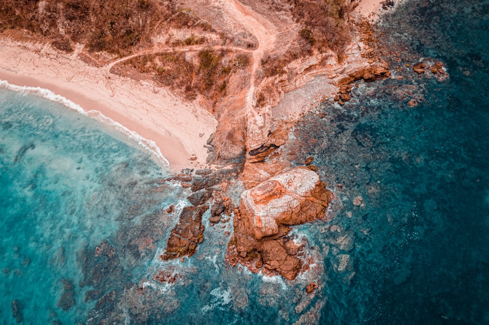 Fotografía aérea de una formación rocosa marrón junto a la orilla del mar