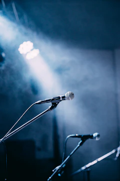 An empty stage bathed in soft white and blue lights with the two faces of drama subtly projected on the backdrop.
