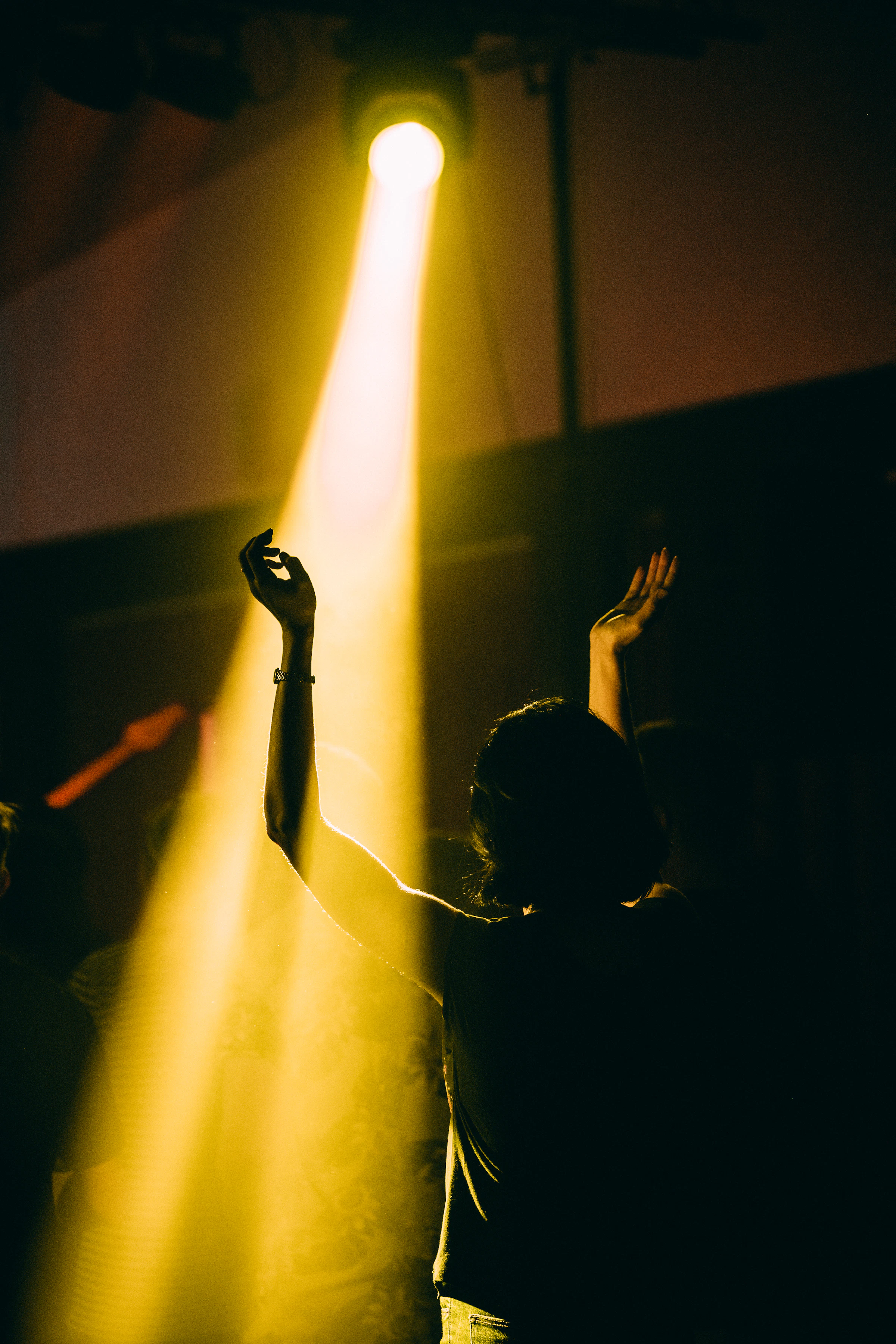 Hands raised in worship under warm light